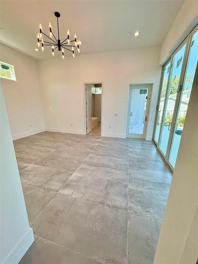 empty room featuring concrete flooring and a notable chandelier