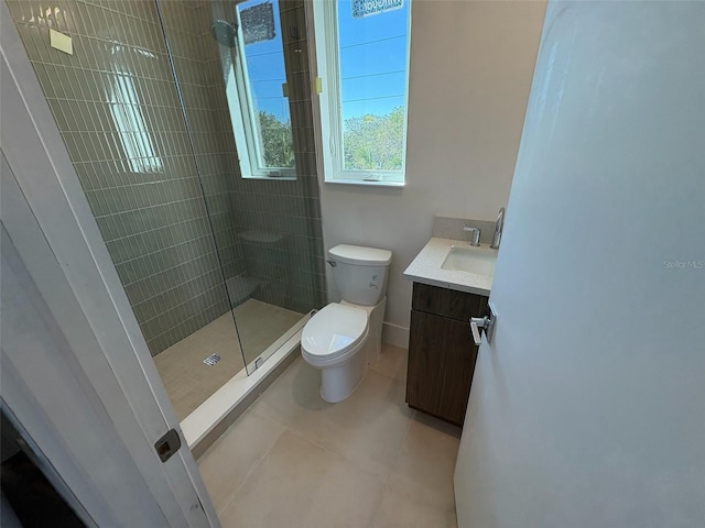 bathroom with tiled shower, tile patterned flooring, vanity, and toilet