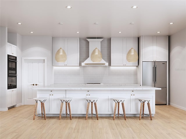 kitchen featuring high end refrigerator, light wood-type flooring, a center island, and a breakfast bar area