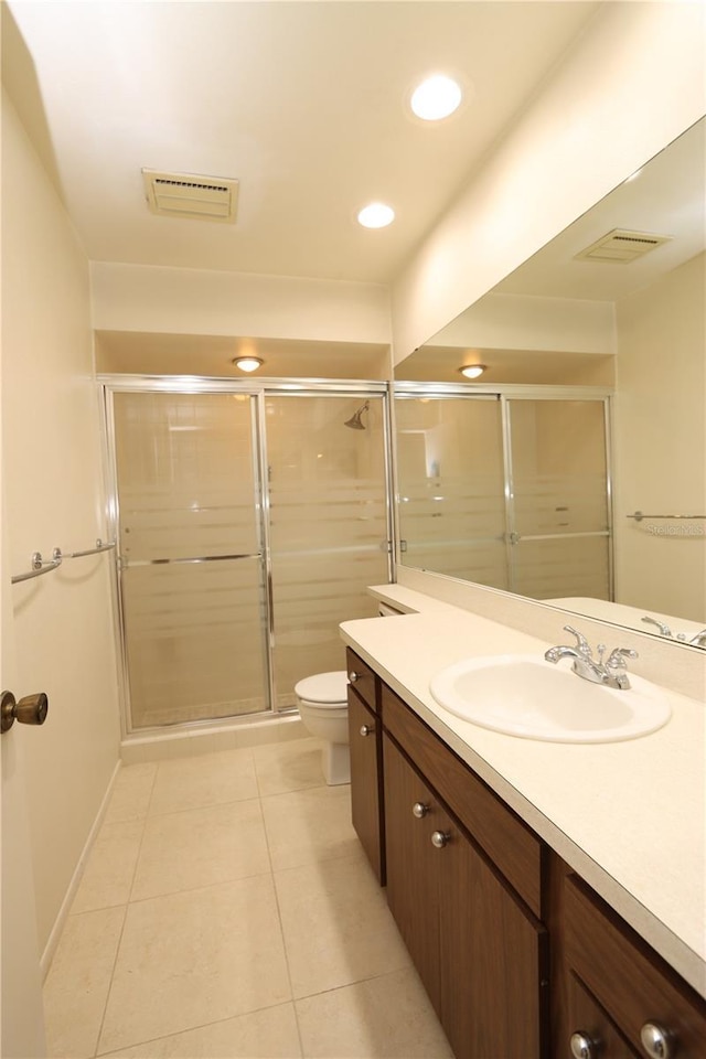 bathroom with tile patterned floors, vanity, a shower with shower door, and toilet