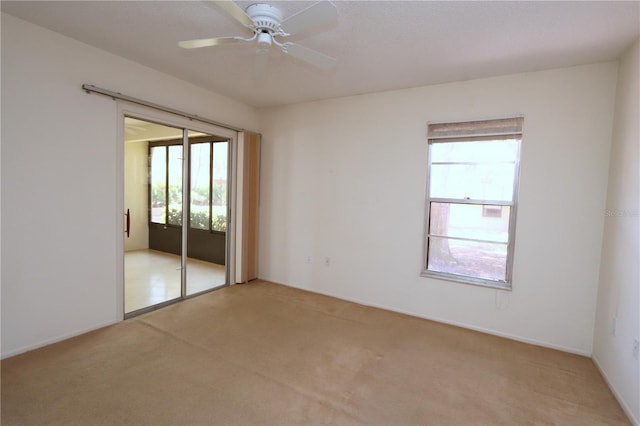 carpeted spare room with ceiling fan and plenty of natural light