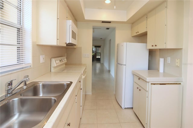 kitchen with backsplash, white appliances, sink, white cabinetry, and light tile patterned flooring