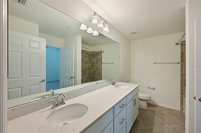 1020 Tidewater Shores Loop Unit 108, Bradenton, FL 34208 - bathroom featuring double vanity, a tile shower, tile patterned flooring, and a textured ceiling