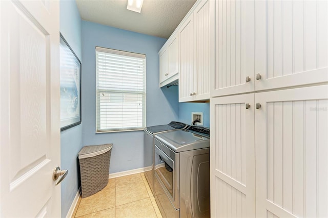 laundry room with washer and dryer, light tile patterned flooring, cabinets, and a textured ceiling