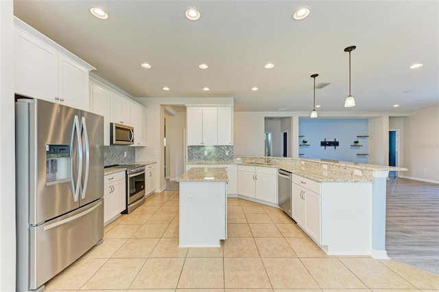 kitchen featuring a center island, white cabinets, decorative backsplash, appliances with stainless steel finishes, and kitchen peninsula