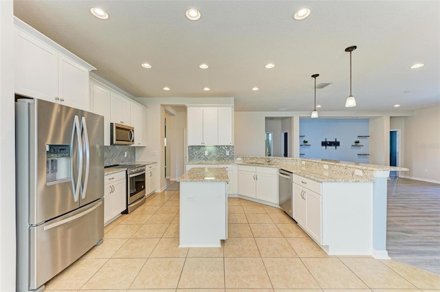 kitchen featuring appliances with stainless steel finishes, white cabinets, decorative light fixtures, a kitchen island, and kitchen peninsula