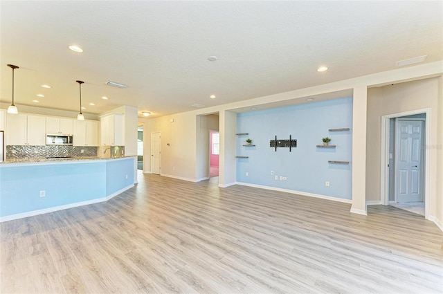 unfurnished living room featuring light wood-type flooring and a textured ceiling