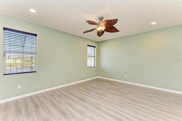 empty room with light hardwood / wood-style floors, ceiling fan, and a textured ceiling