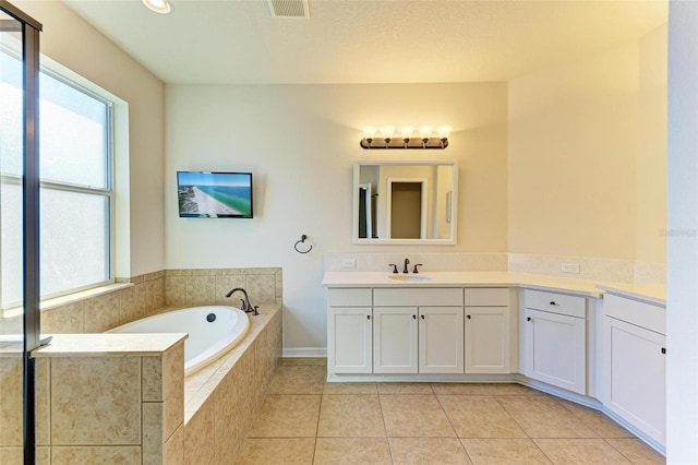 bathroom featuring vanity, tile patterned flooring, and tiled tub