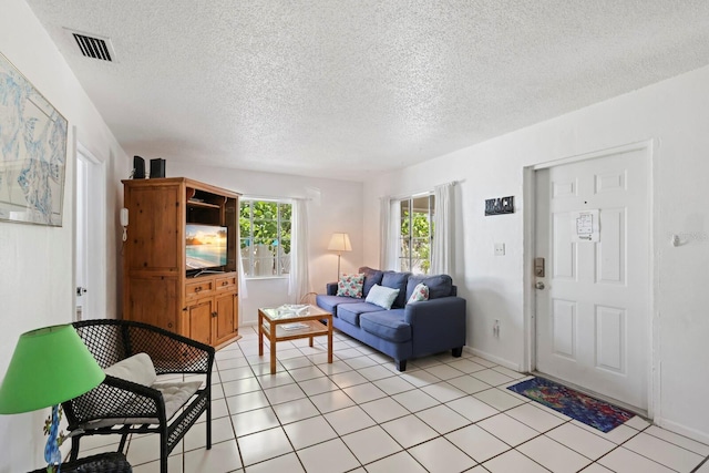 living room with a textured ceiling and light tile patterned flooring