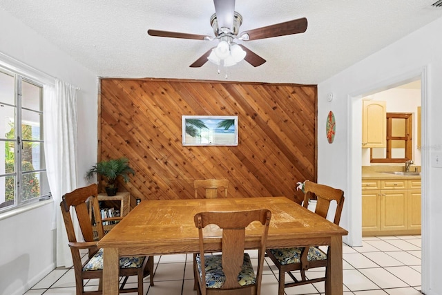 dining area with light tile patterned floors, sink, and wooden walls