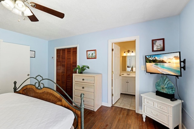 bedroom with a textured ceiling, ceiling fan, dark wood-type flooring, connected bathroom, and a closet