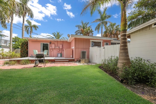 rear view of property with a lawn, cooling unit, and a patio area