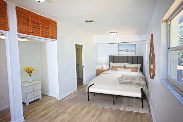 bedroom with a textured ceiling and dark hardwood / wood-style floors