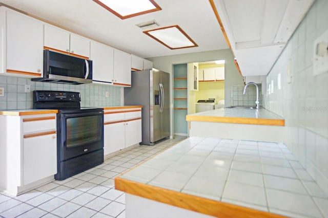 kitchen with appliances with stainless steel finishes, backsplash, tile countertops, and white cabinetry