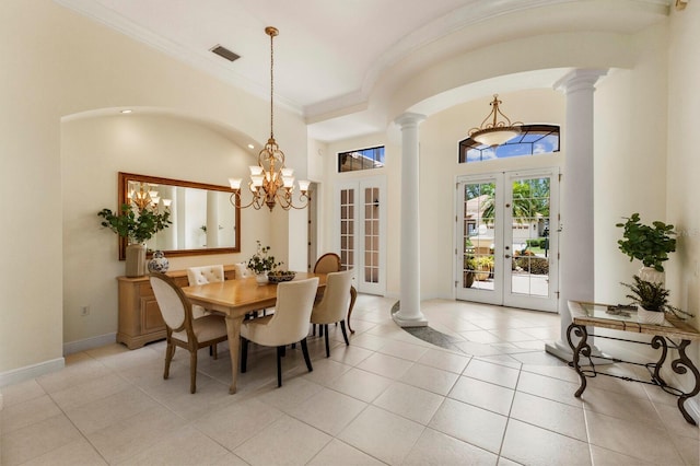 tiled dining space with decorative columns, ornamental molding, a towering ceiling, and french doors