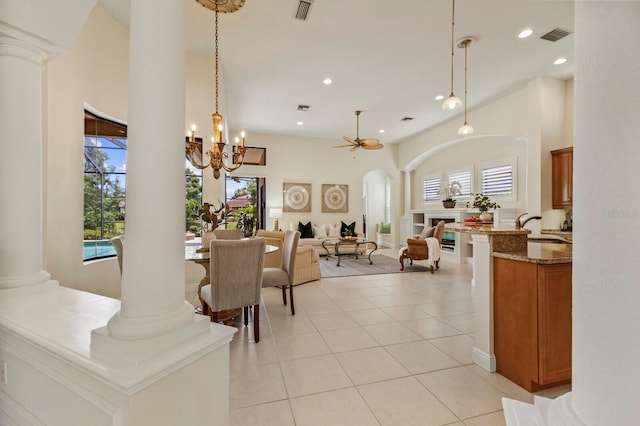 dining room with ornate columns, light tile patterned flooring, sink, and ceiling fan with notable chandelier