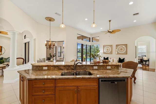 kitchen with sink, stainless steel dishwasher, an island with sink, ceiling fan, and decorative columns