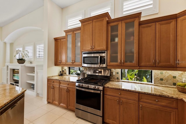 kitchen with light stone counters, backsplash, stainless steel appliances, and light tile patterned flooring