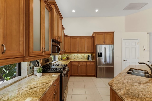 kitchen featuring tasteful backsplash, sink, light stone countertops, and appliances with stainless steel finishes