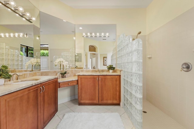 bathroom with tile patterned flooring, vanity, and a tile shower