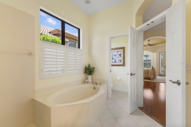 bathroom with tiled bath, tile patterned floors, and toilet