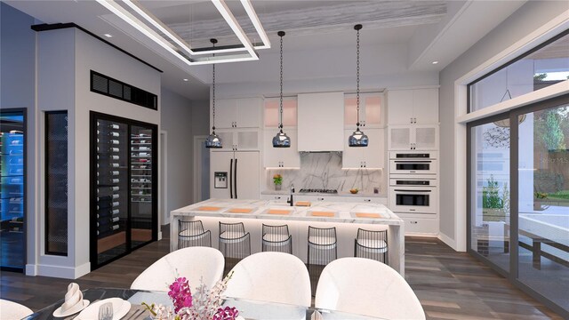 kitchen featuring backsplash, a center island with sink, built in fridge, white cabinets, and double oven