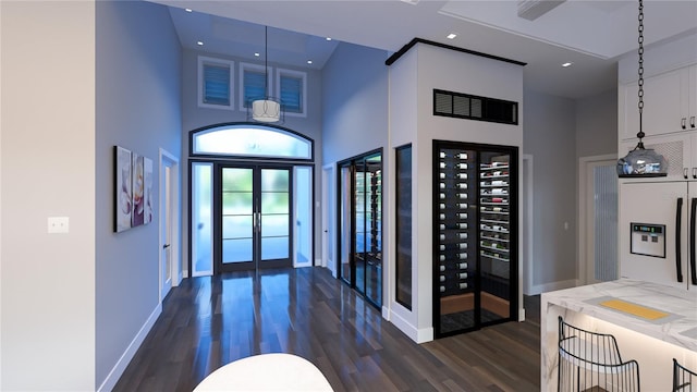 entrance foyer with french doors, a towering ceiling, and dark hardwood / wood-style floors