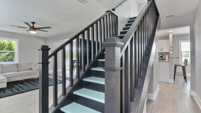 staircase with ceiling fan and a healthy amount of sunlight