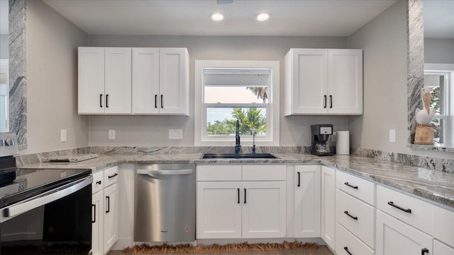 kitchen with white cabinets, stainless steel appliances, light stone countertops, and sink