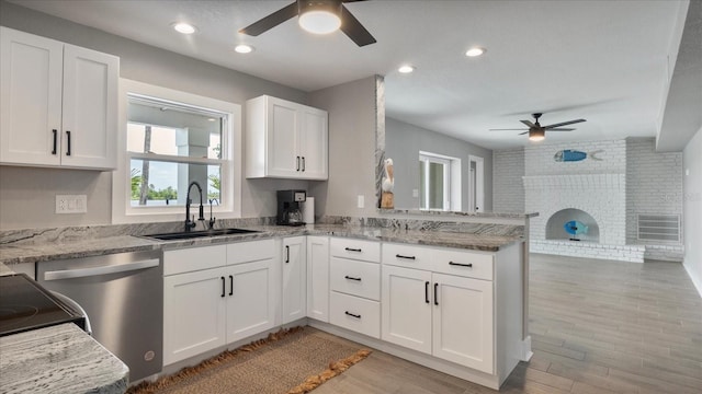 kitchen featuring sink, stainless steel dishwasher, light stone countertops, white cabinetry, and kitchen peninsula