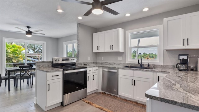 kitchen featuring white cabinets, sink, ceiling fan, kitchen peninsula, and stainless steel appliances