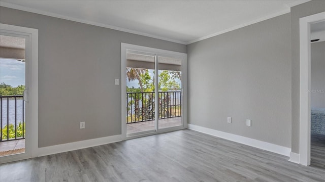 empty room featuring light hardwood / wood-style floors, a water view, and crown molding