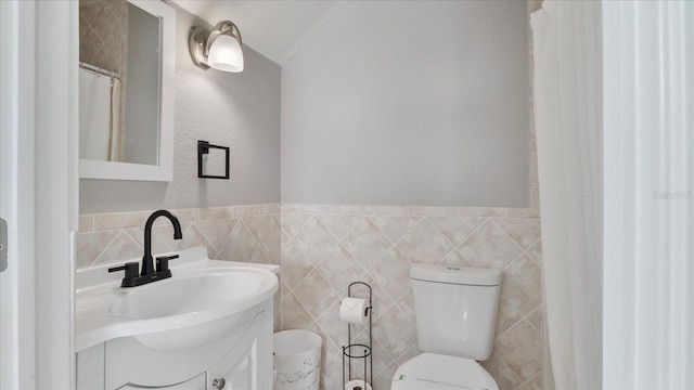 bathroom with vanity, toilet, and tile walls