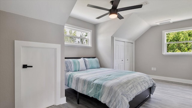 bedroom with multiple windows, ceiling fan, a closet, and lofted ceiling