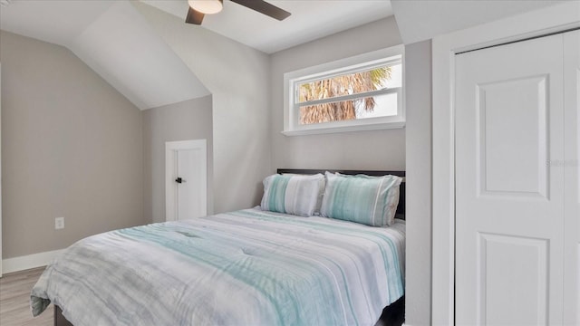 bedroom with ceiling fan, light hardwood / wood-style floors, a closet, and vaulted ceiling