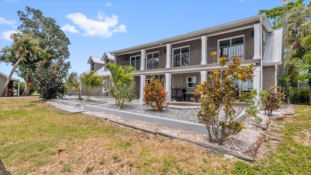 back of house with a lawn and a balcony