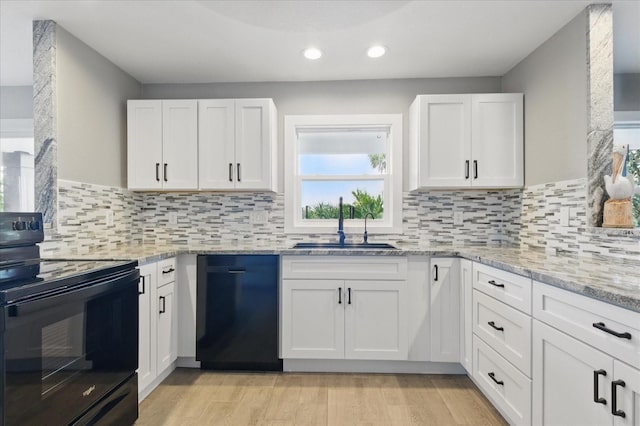 9610 SW Yacht Dr, Arcadia, FL 34269 - kitchen with light stone countertops, a sink, light wood finished floors, white cabinetry, and black appliances