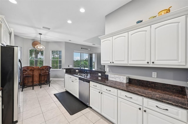 kitchen with appliances with stainless steel finishes, dark stone counters, sink, decorative light fixtures, and white cabinets