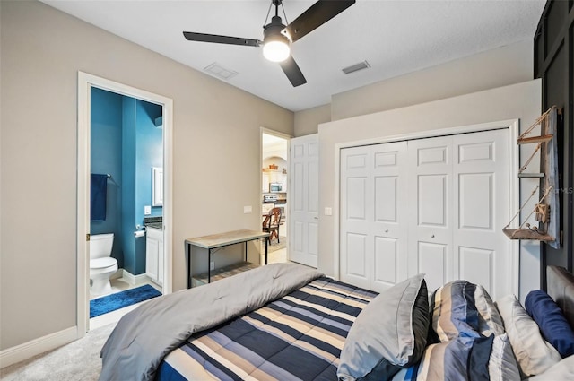 bedroom featuring a closet, light colored carpet, ceiling fan, and ensuite bathroom