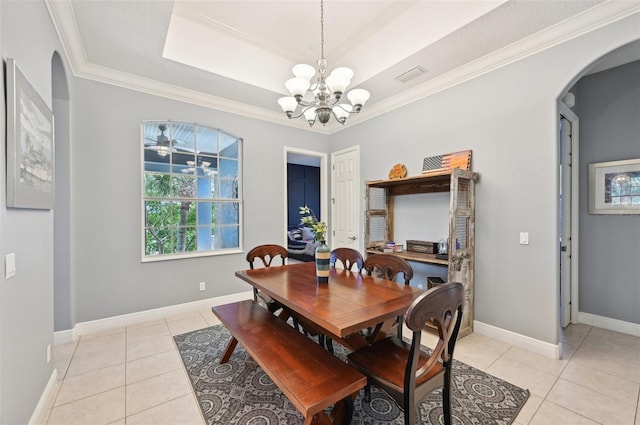 tiled dining space featuring a raised ceiling, crown molding, and a chandelier