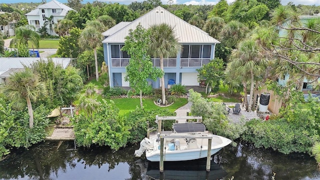 exterior space featuring a sunroom, a water view, and a lawn