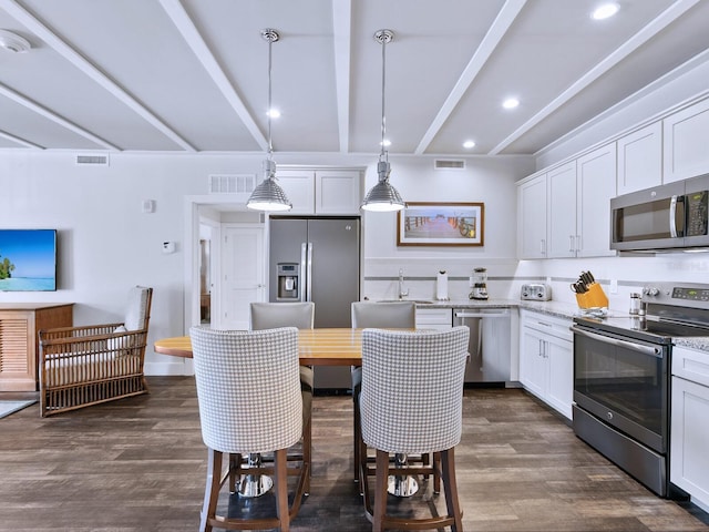 kitchen with dark hardwood / wood-style floors, beam ceiling, hanging light fixtures, white cabinets, and appliances with stainless steel finishes