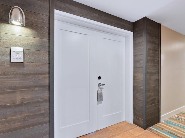 interior space with hardwood / wood-style flooring and wooden walls