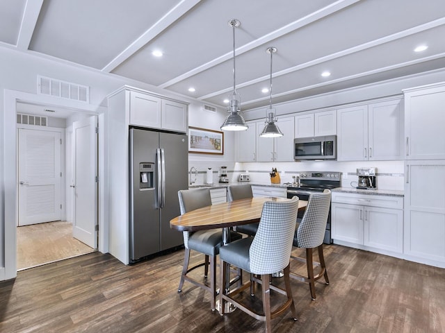 kitchen featuring stainless steel appliances, pendant lighting, beam ceiling, dark hardwood / wood-style floors, and white cabinetry