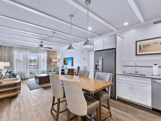 dining area with beamed ceiling, ceiling fan, sink, and dark wood-type flooring