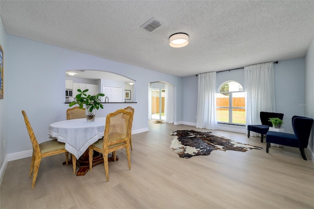 dining room featuring a textured ceiling and light hardwood / wood-style floors