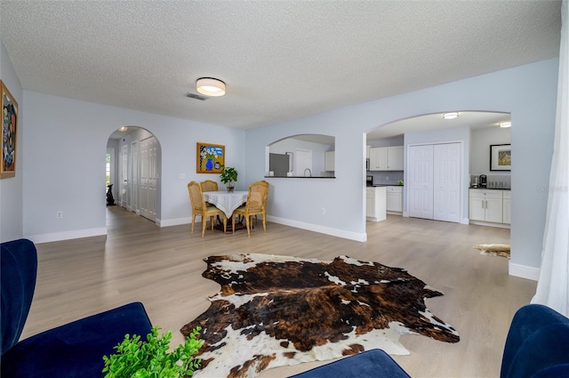 living room with a textured ceiling and light wood-type flooring