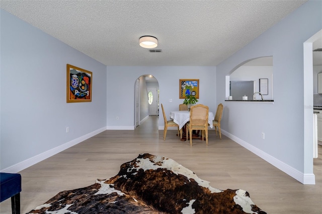 dining space with a textured ceiling and light hardwood / wood-style flooring