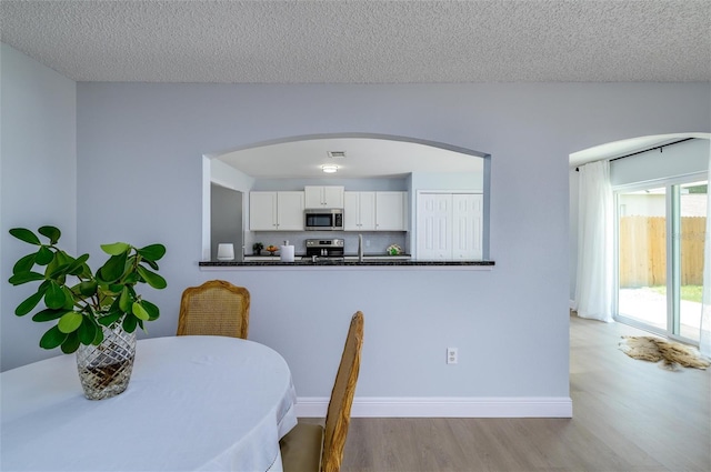 dining area featuring sink, light wood-type flooring, and a textured ceiling